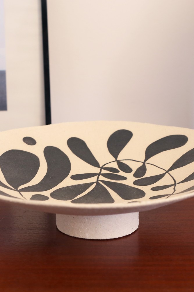Handmade stoneware footed bowl with a black leaf pattern, crafted in Paris.