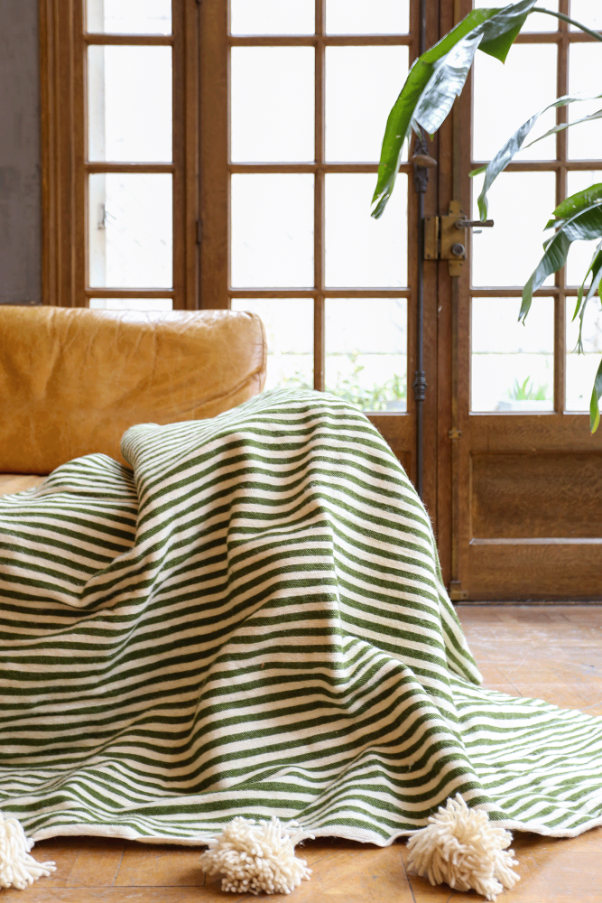 Handmade Berber wool blanket with white pompoms and khaki stripes, crafted in Morocco.