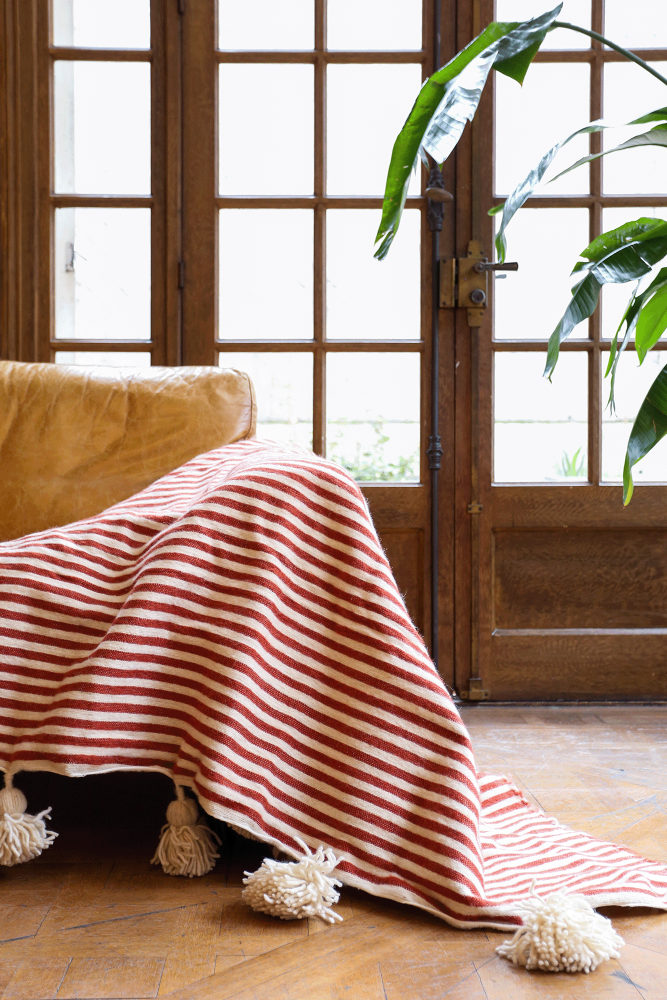 Berberse deken met witte pompons en rode strepen van wol, handgemaakt in Marokko.