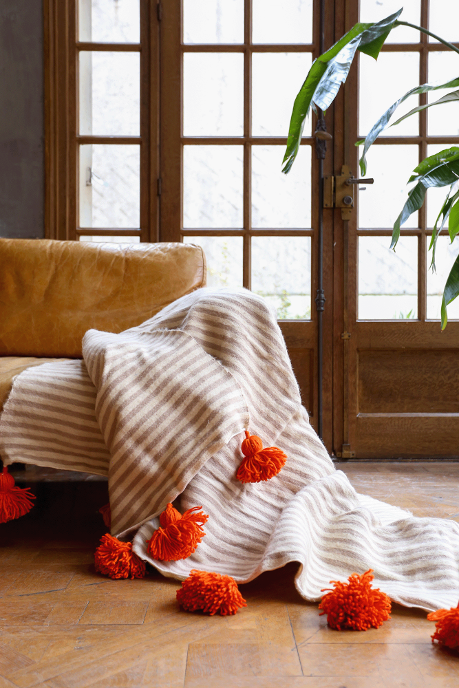 Plaid berbère blanc à pompon orange et rayures taupes en laine confectionné à la main au Maroc