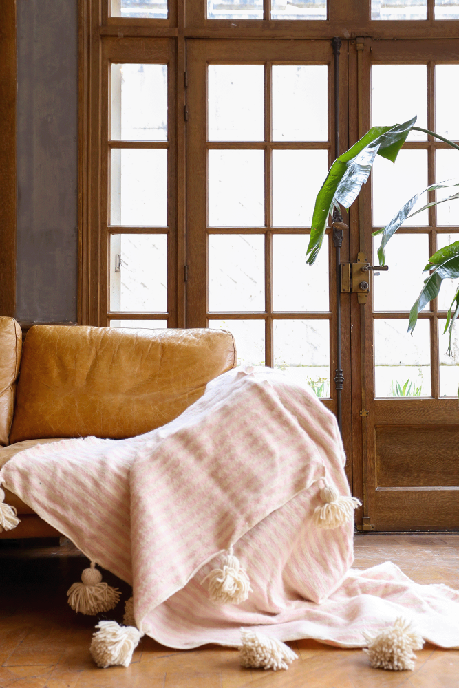 Handcrafted Moroccan wool Berber blanket with white pompoms and pink stripes.